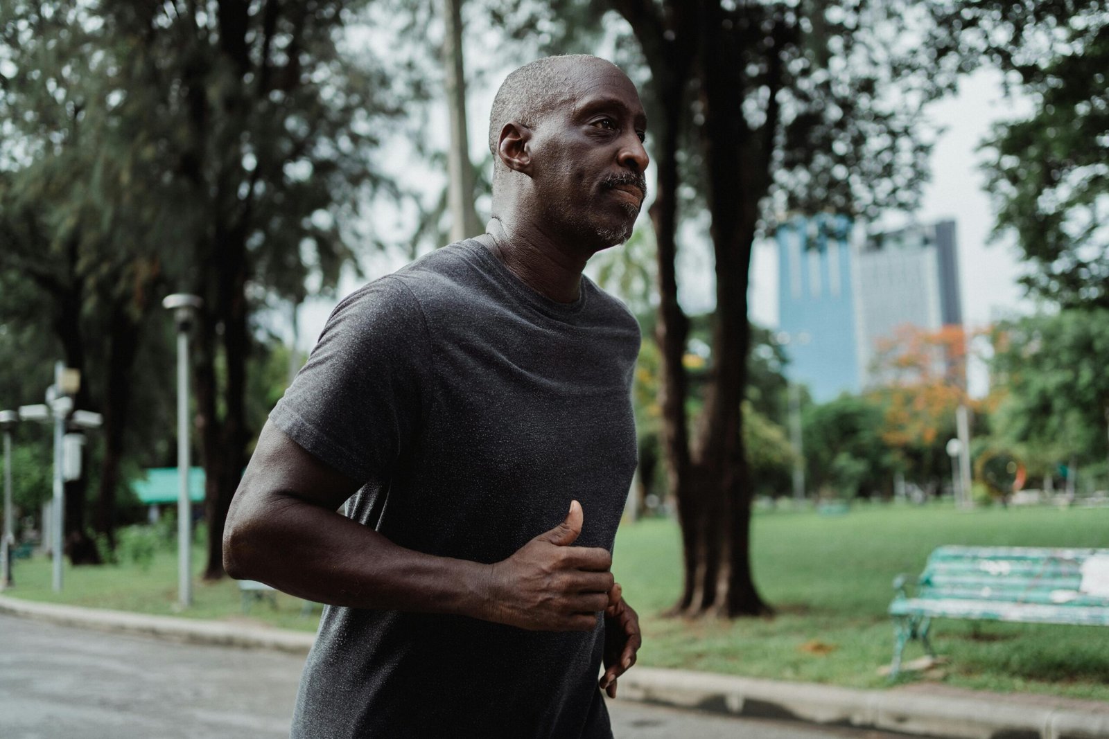 No One Cares How Fast You Are — And That’s a Good Thing A focused black man jogging in a city park, promoting healthy lifestyle and wellbeing.
